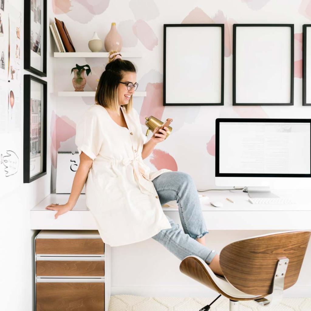 Vrouw zit ontspannen op een stoel in een lichte kamer met ingelijste foto's aan de muur